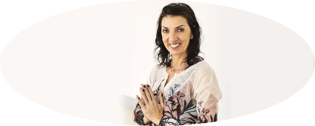 Femme souriante en tenue de yoga, mains jointes devant elle.