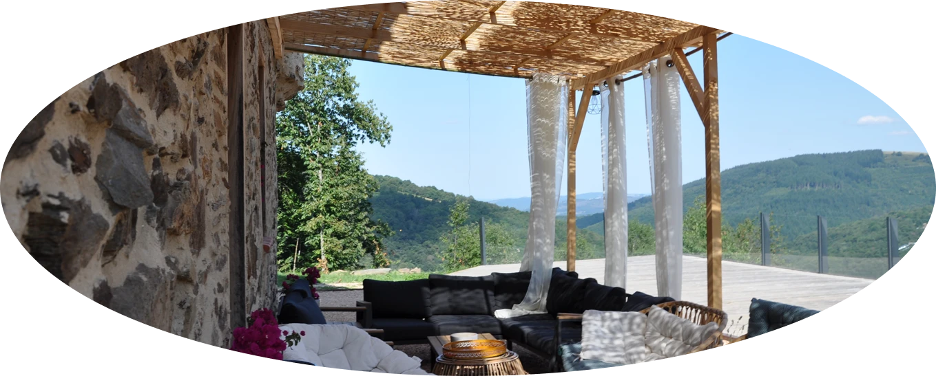 Terrasse ombrag&eacute;e avec vue sur montagnes et canap&eacute; ext&eacute;rieur.