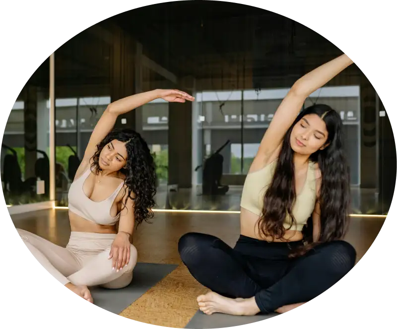 Deux femmes faisant du yoga en salle, pos&eacute;es en &eacute;tirement lat&eacute;ral.