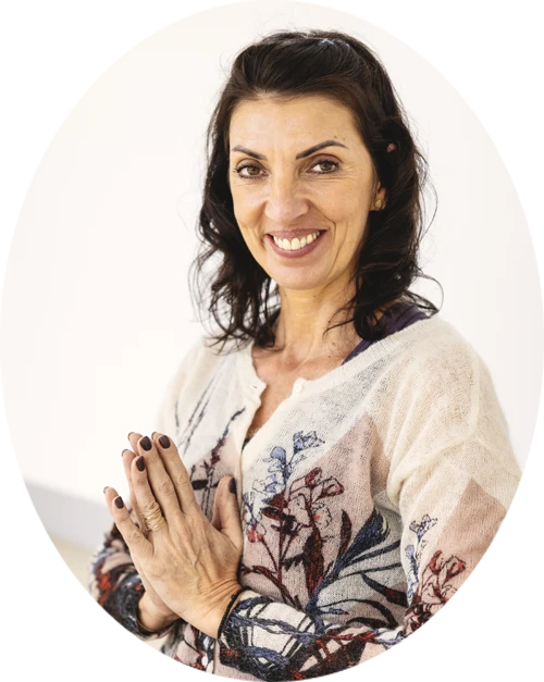 Femme souriante avec les mains jointes, portant un pull &agrave; motifs floraux.