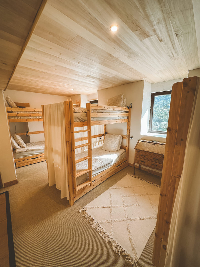 Chambre avec lits superposés en bois et tapis beige.
