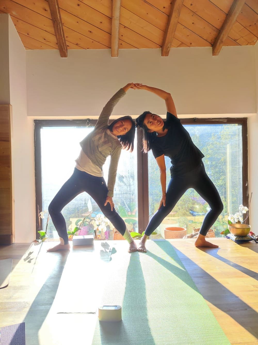 Deux personnes font du yoga ensemble dans une posture sym&eacute;trique.