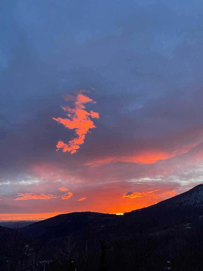 Coucher de soleil vibrant sur montagnes sombres avec nuages color&eacute;s.