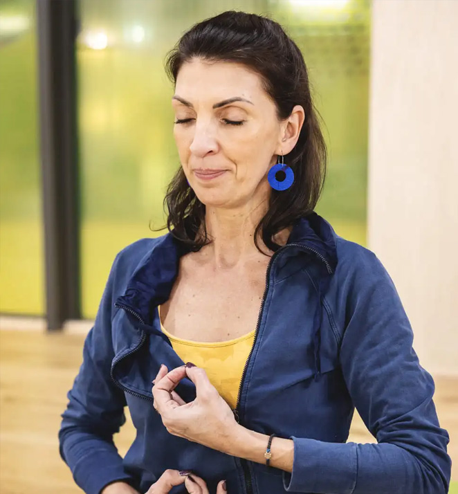 Femme m&eacute;ditant en int&eacute;rieur, yeux ferm&eacute;s, en tenue d&eacute;contract&eacute;e.