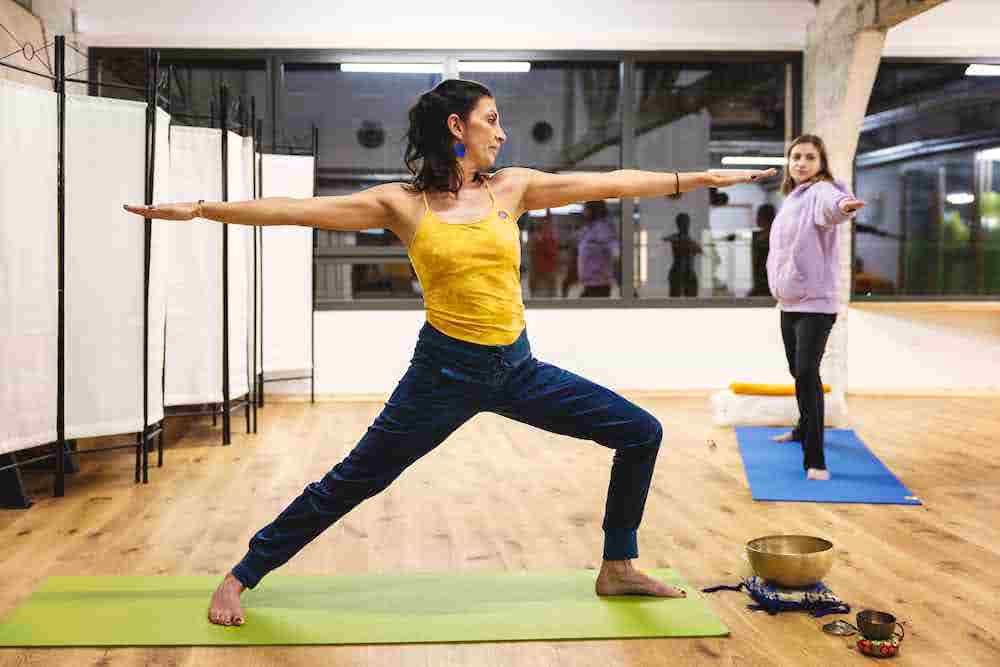 Deux femmes pratiquant le yoga dans une salle lumineuse.