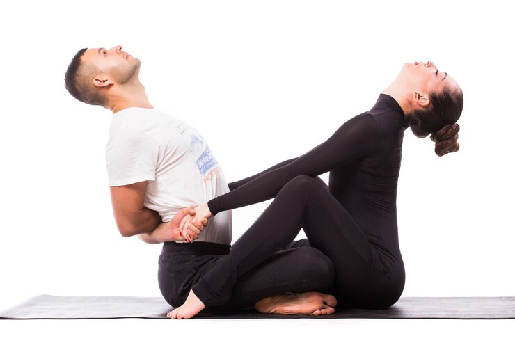 Couple faisant du yoga en posture assise, sur fond blanc.