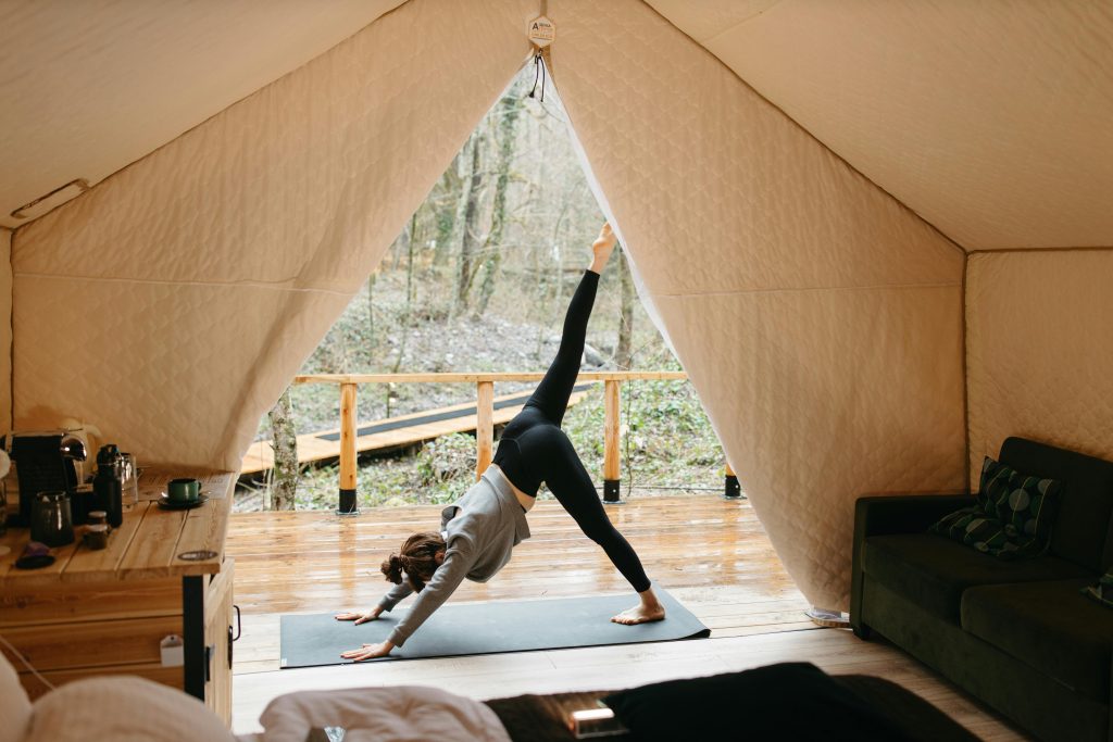 Femme faisant du yoga dans une tente avec vue sur la forêt.