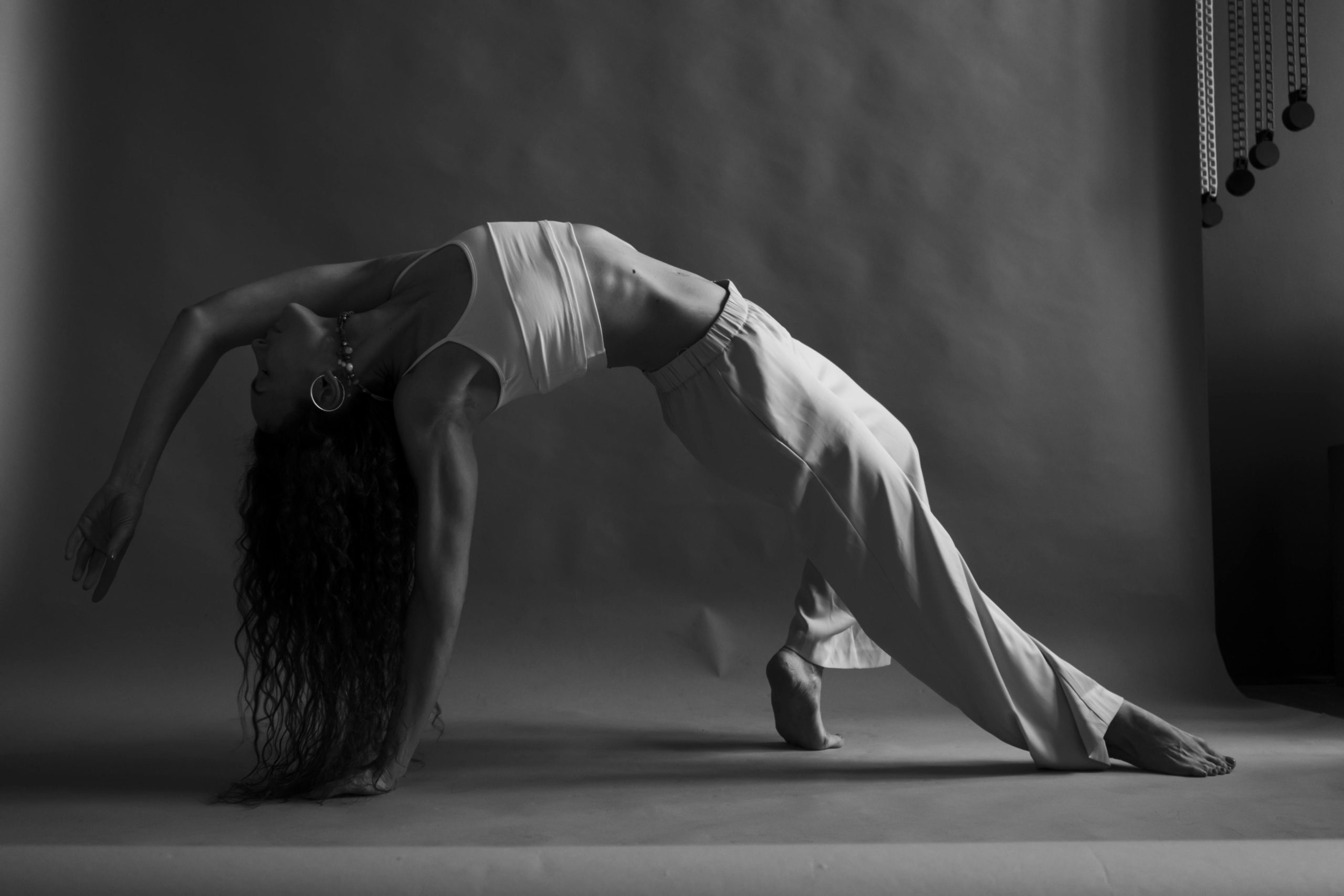 Une femme effectue une pose de yoga en arrière dans un studio.