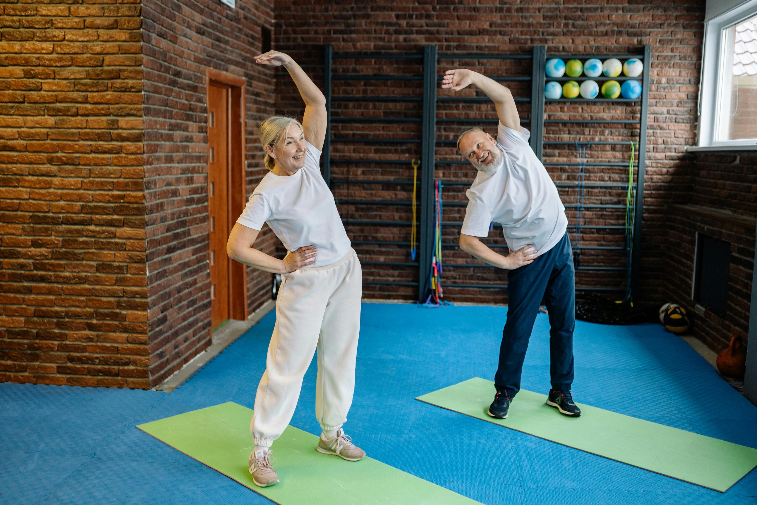 Personnes âgées s'étirant sur des tapis de yoga dans une salle de sport.