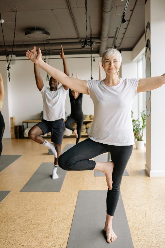 Personnes pratiquant le yoga dans une salle lumineuse.