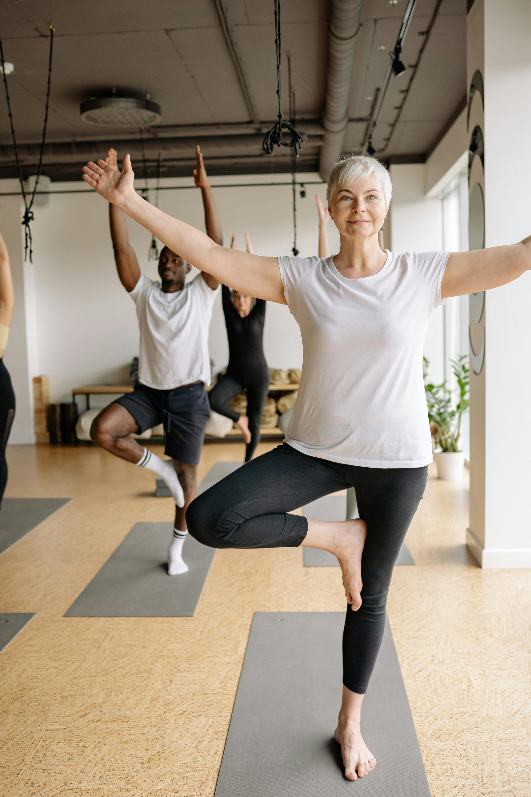 Personnes pratiquant le yoga dans une salle lumineuse.