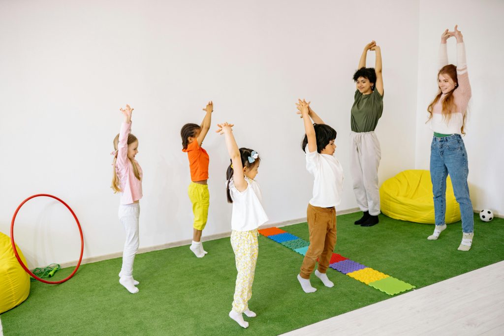 Enfants et adultes faisant des &eacute;tirements dans une salle de jeux color&eacute;e.