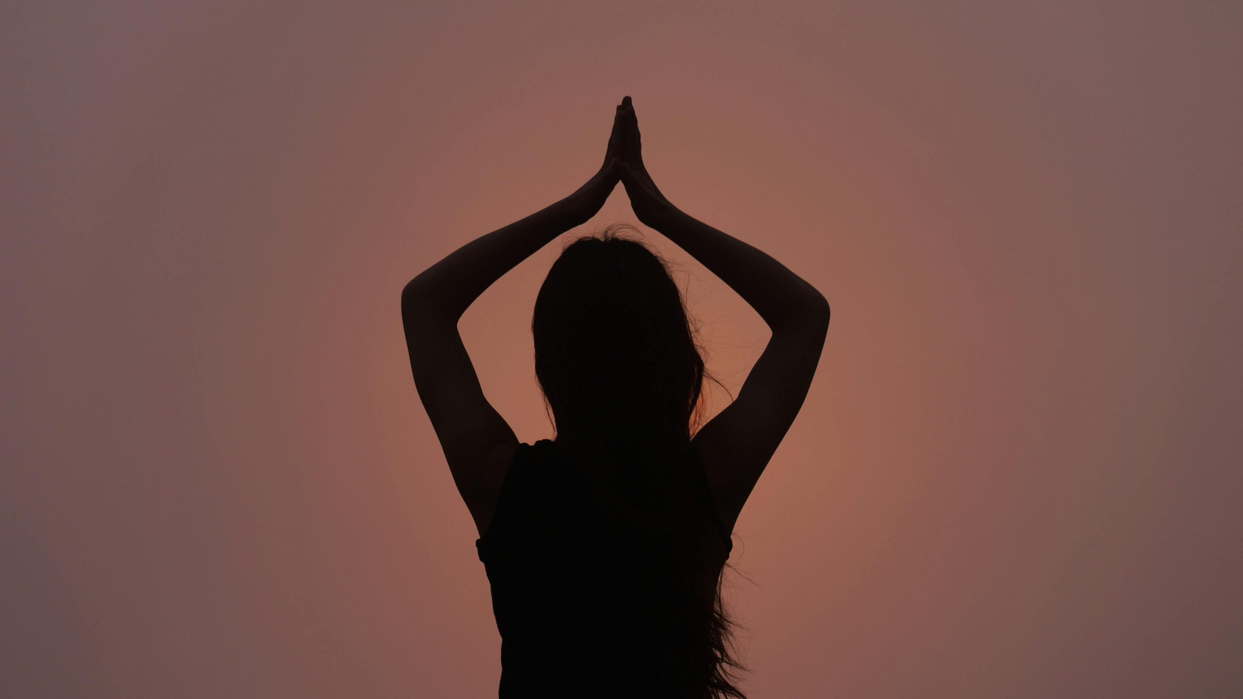 Silhouette d'une personne méditant au coucher du soleil.