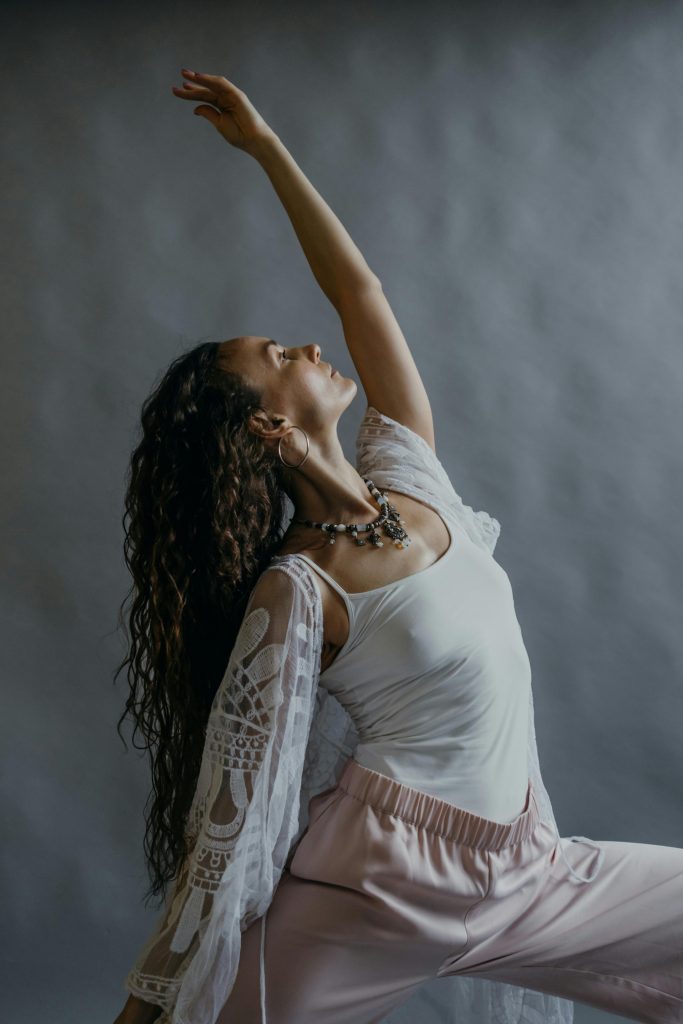 Femme dansant en tenue blanche et rose, bras lev&eacute;.