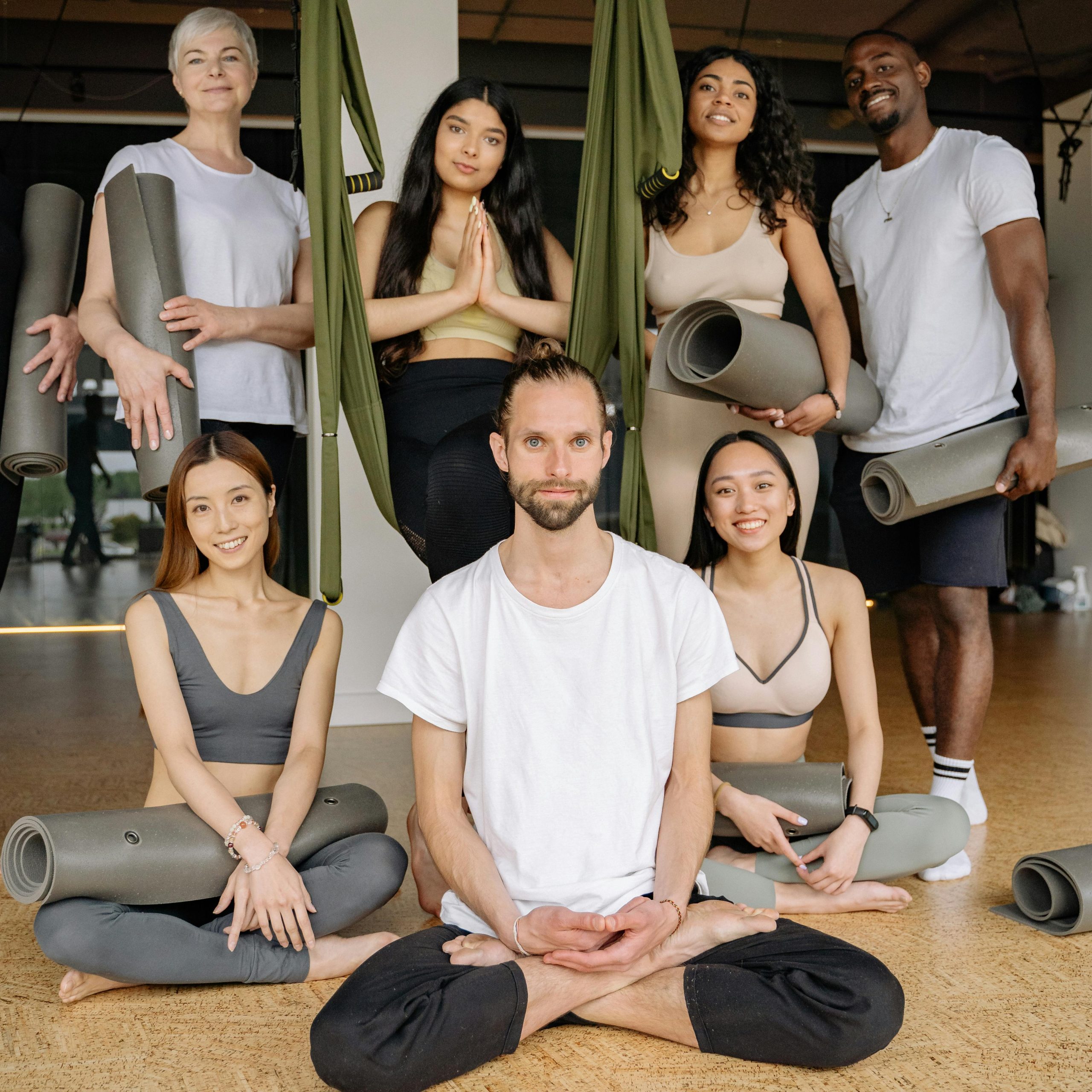Un groupe de personnes avec des tapis de yoga dans une salle de sport.