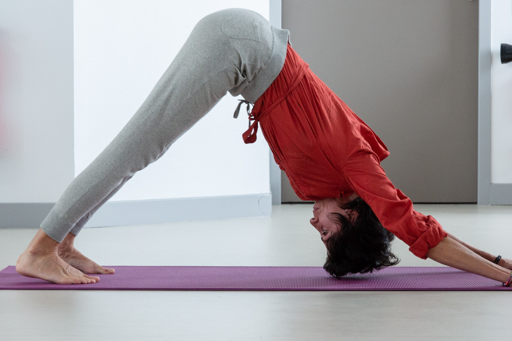 Femme en posture du chien t&ecirc;te en bas sur un tapis de yoga.