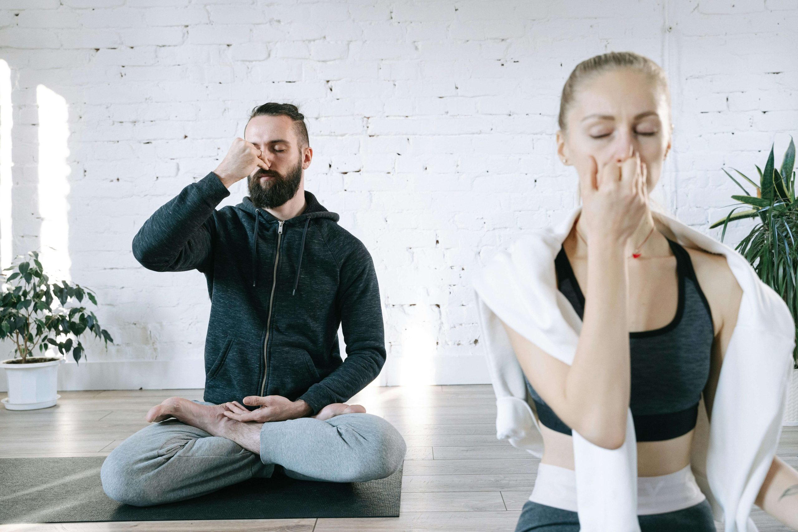 Deux personnes pratiquant le pranayama dans une salle de yoga.