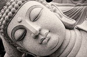 Statue de Bouddha en pierre, visage serein, yeux fermés.