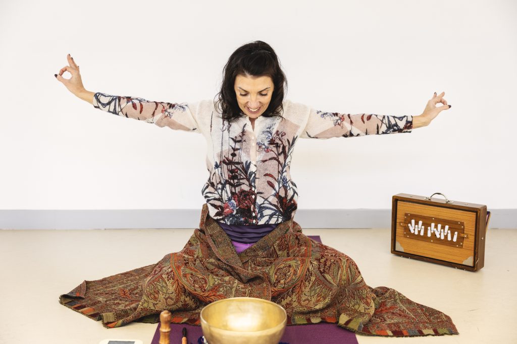 Femme méditant avec un bol tibétain, un harmonium et un tissu coloré.
