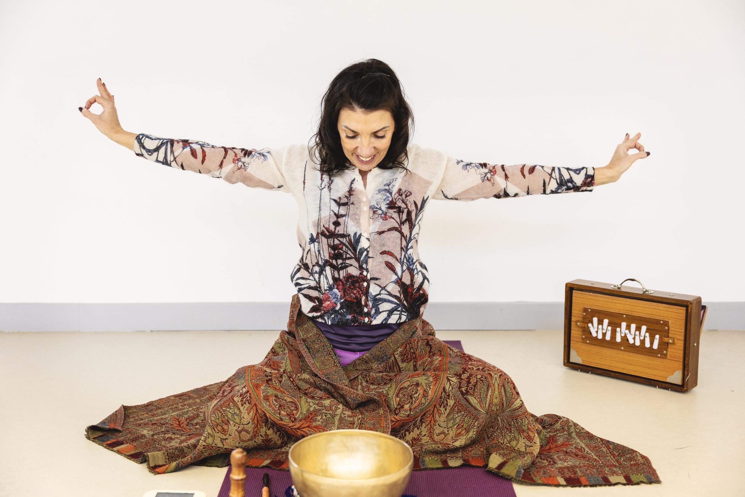 Femme méditant avec un bol tibétain, un harmonium et un tissu coloré.