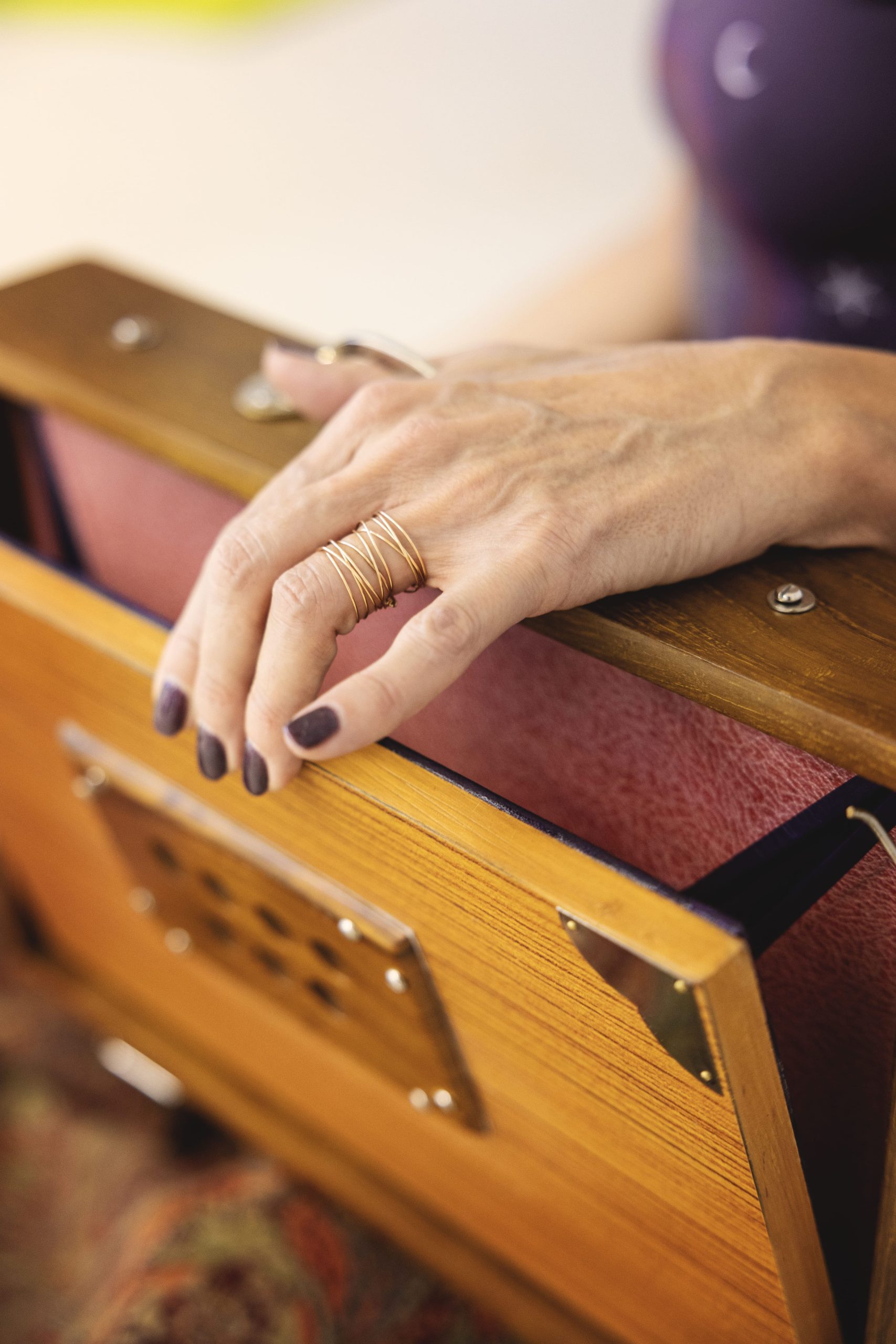 Main ornée de bagues posée sur un harmonium en bois.