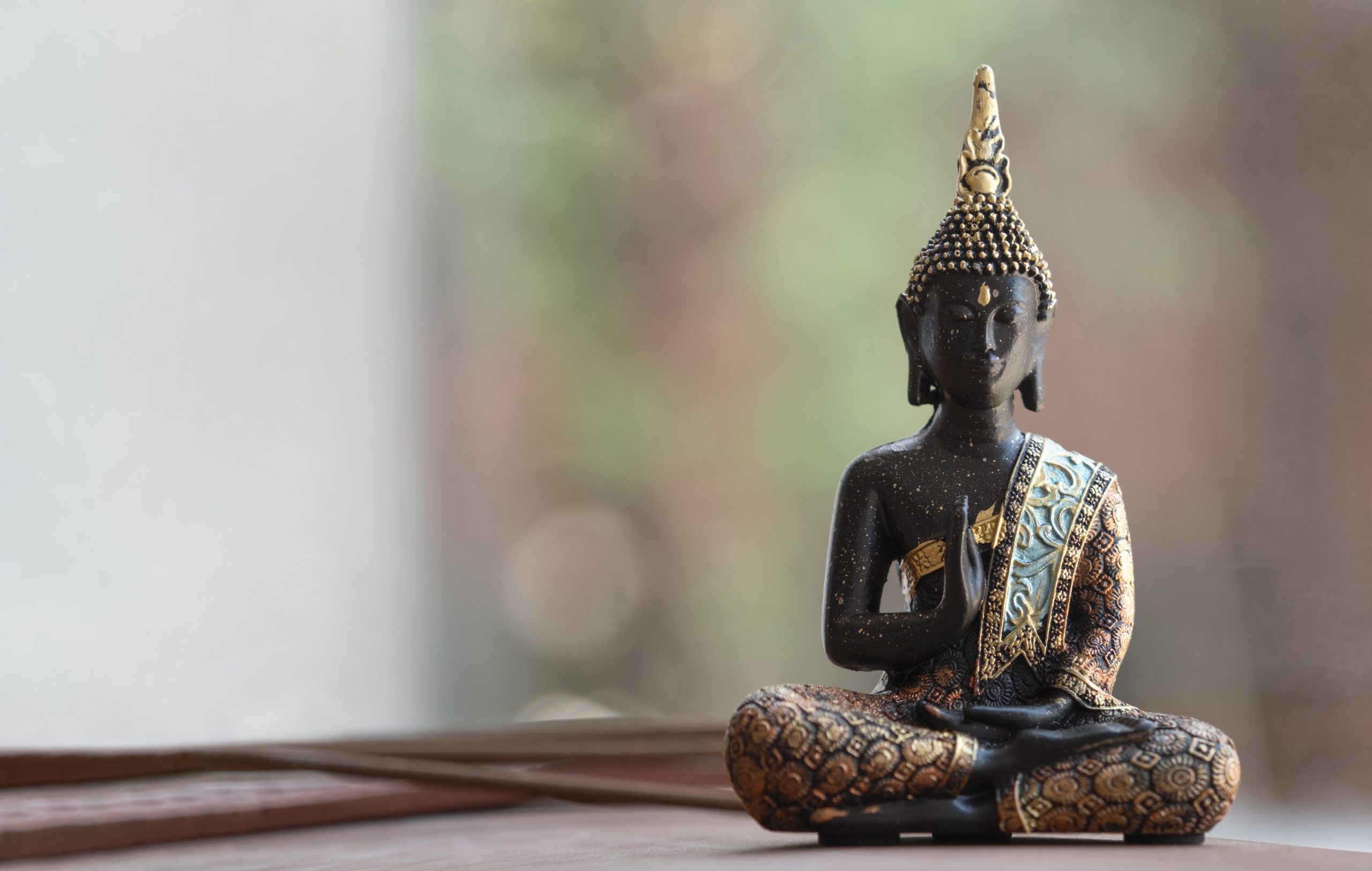 Statue de Bouddha assise avec ornements dorés, fond flou.