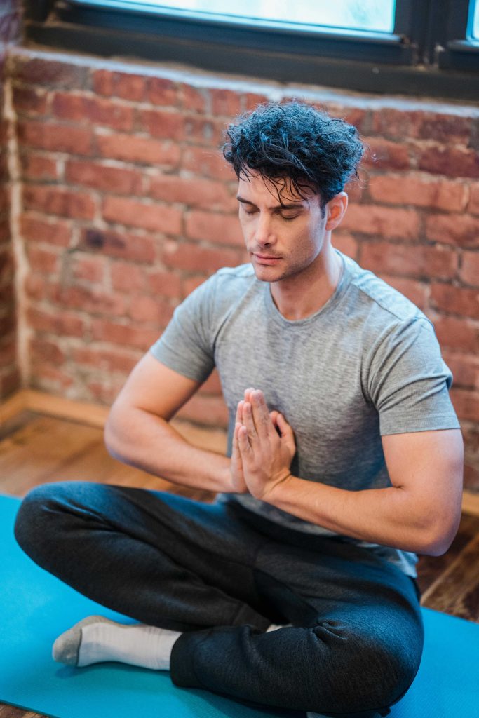 Homme m&eacute;ditant en position de lotus sur un tapis de yoga.